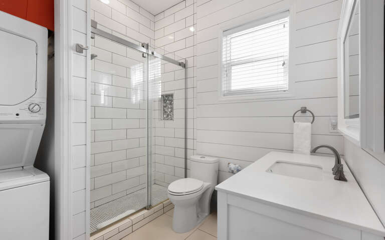 Unwind in your bright, modern bathroom featuring a spacious glass shower, crisp white subway tiles, and fresh towels waiting for you.