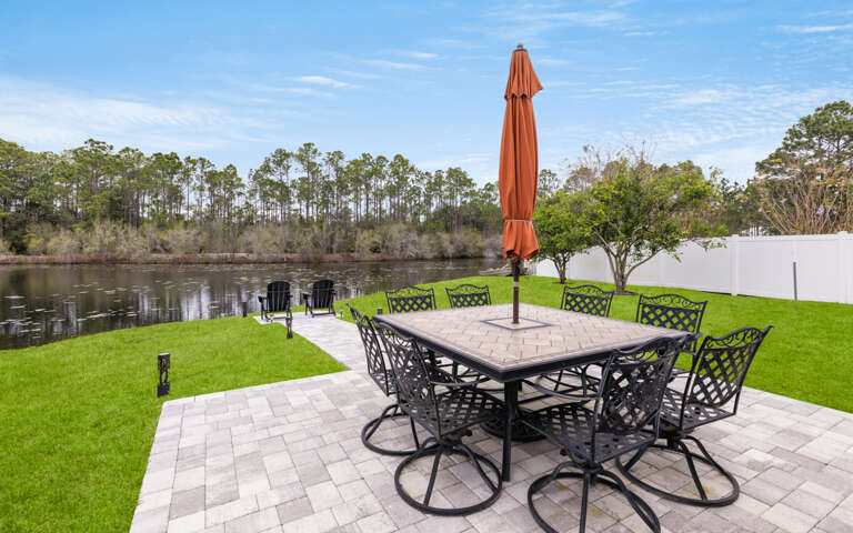 Outdoor Patio With Furniture By Water At Vacation Rental