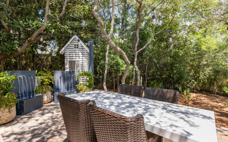 Outdoor Dining Area With Wicker Chairs And Table Surrounded By Trees
