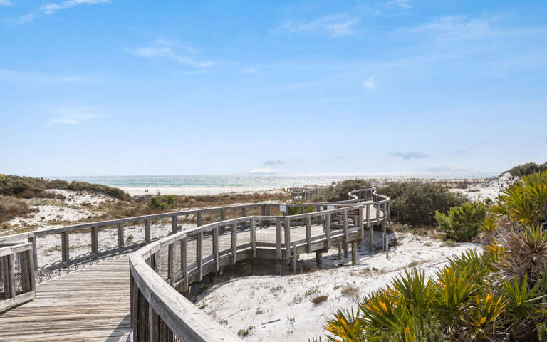 Wooden Walkway Winding Through White Dunes Leading To A Serene Sea
