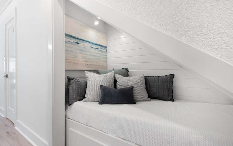 Cozy nook where you can unwind with soft textures and coastal charm tucked beneath the sloped ceiling.