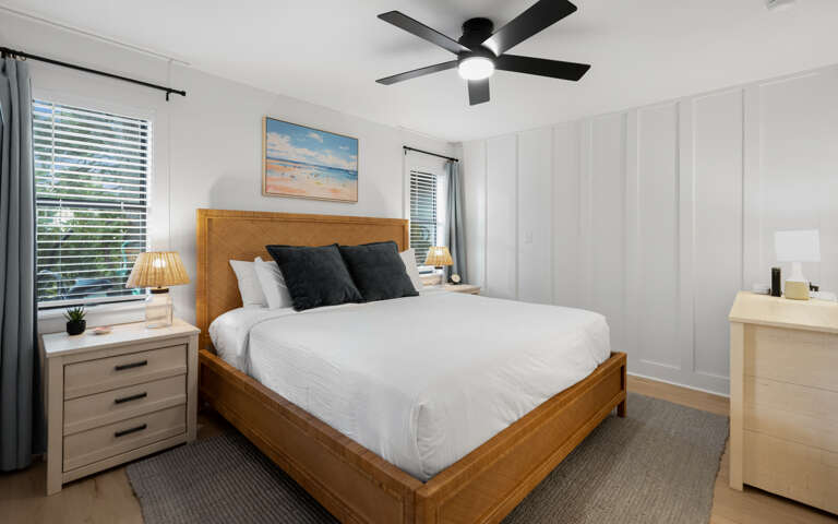Rest peacefully in your serene bedroom with crisp linens, gentle ceiling fan breeze, and coastal artwork creating the perfect atmosphere.