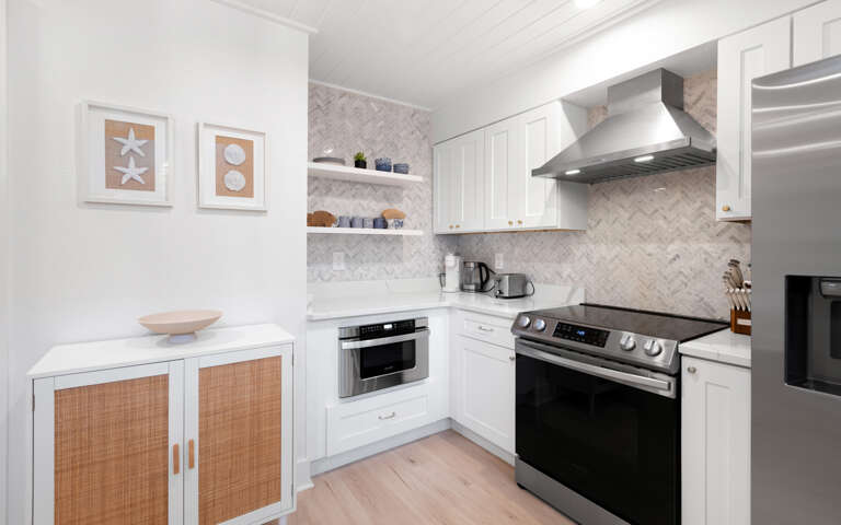 Your stylish kitchen features modern appliances, gleaming white cabinets, and herringbone marble backsplashâperfect for preparing memorable meals during your stay.