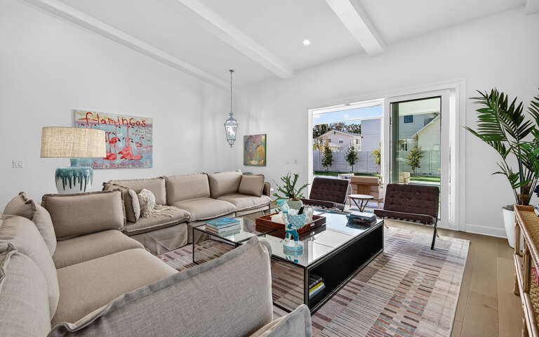 Sink into plush sofas beneath soaring beam ceilings in your bright, modern living space with floor-to-ceiling windows.