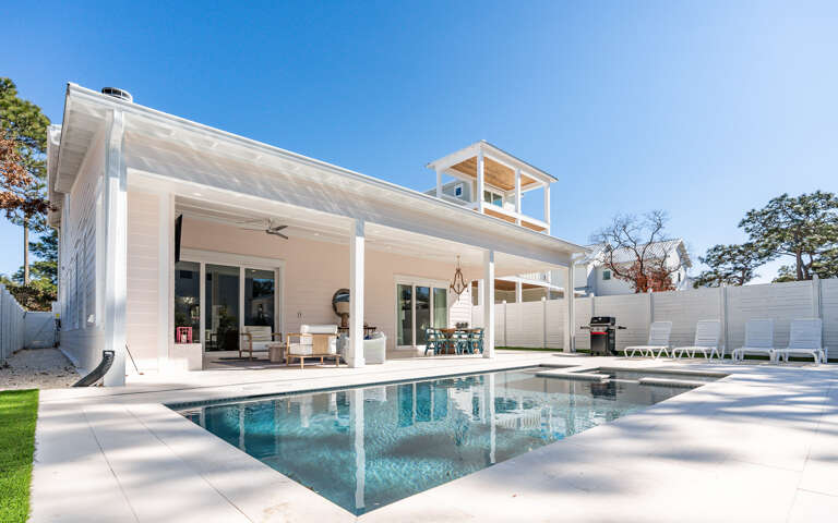 Modern coastal retreat with pristine pool and spacious covered patio for relaxing under sunny skies.