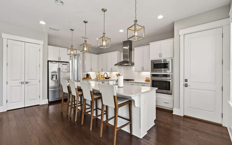 Your gourmet kitchen awaits with sleek white cabinetry, modern appliances, and a spacious island perfect for morning coffee or evening meals together.