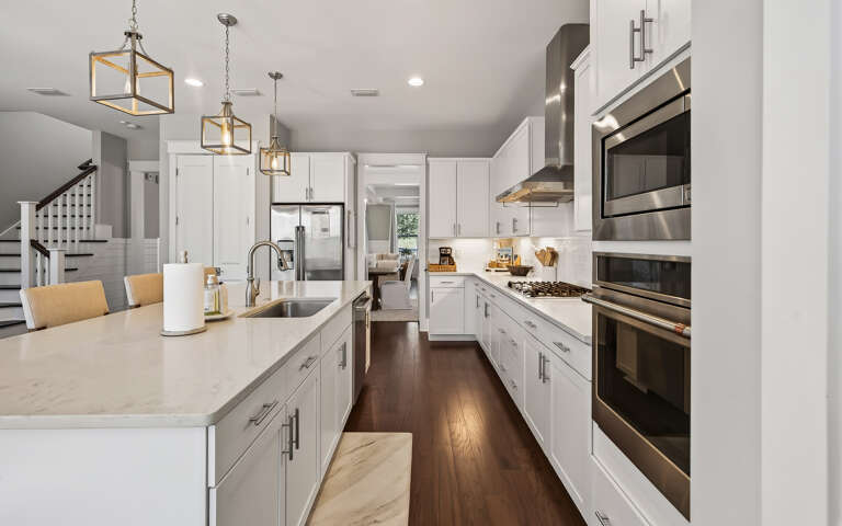 Your gourmet kitchen beckons with pristine white cabinetry, gleaming quartz countertops, and professional-grade stainless steel appliances ready for culinary adventures.
