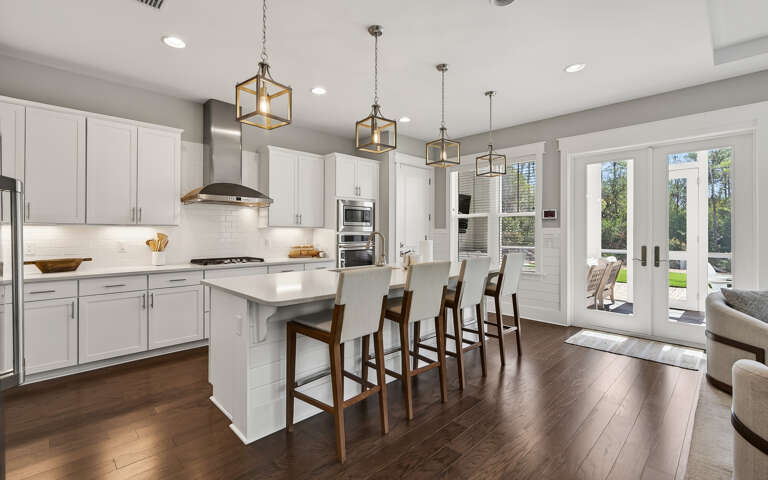Your gourmet kitchen welcomes you with gleaming white cabinets, sleek countertops, and warm pendant lighting perfect for cooking memorable meals together.