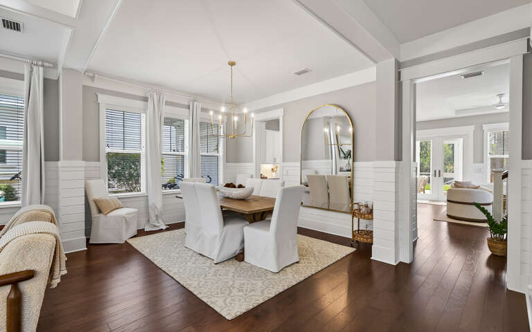 You'll love gathering around this elegant dining table, where natural light streams through large windows as you enjoy meals together.