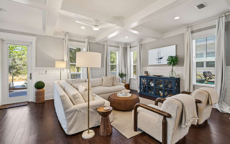 Sink into the plush sectional sofa where coffered ceilings and abundant natural light create your perfect retreat.