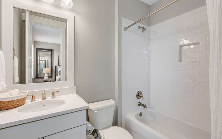 Refresh in your bright, modern bathroom featuring a deep soaking tub, rainfall shower, and pristine white subway tile surrounds.