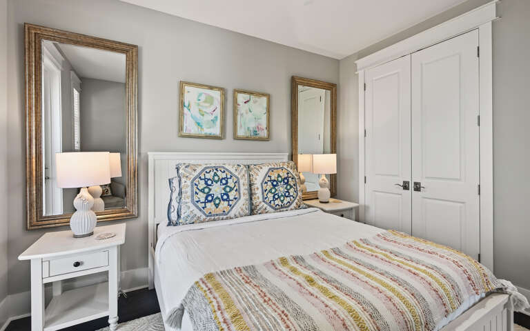 Sink into crisp white linens and colorful Mediterranean patterns in your serene bedroom retreat, complete with thoughtful touches and elegant storage.