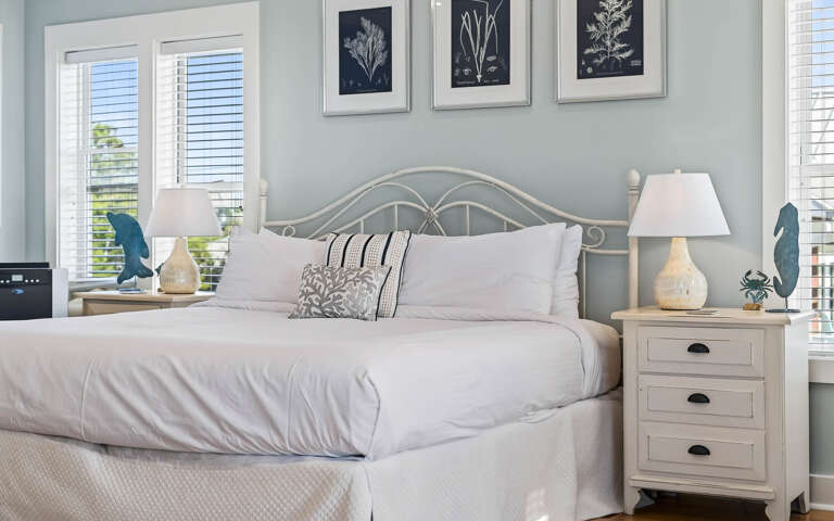 Drift off in your serene coastal retreat with crisp white linens and elegant botanical artwork creating the perfect peaceful sanctuary.