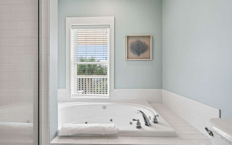 Sink into your private jetted tub beneath soothing mint walls, where natural light streams through white blinds creating your perfect spa retreat.