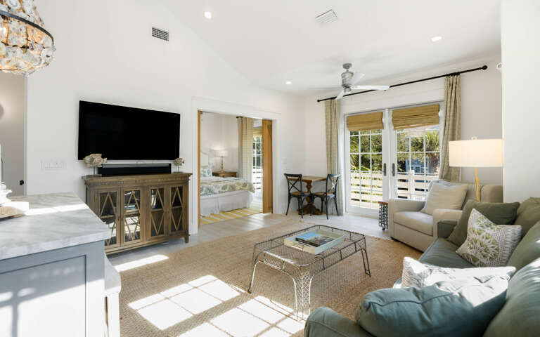 Relax in your bright living area with plush seating, large TV, and natural light streaming through French doors to your private balcony.