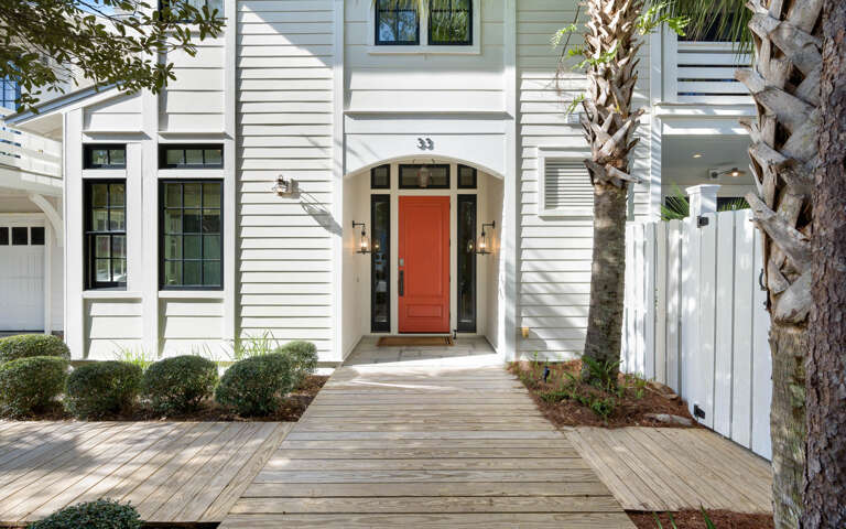 Elegant coastal entrance with striking orange door welcomes guests to this beautifully designed vacation home.