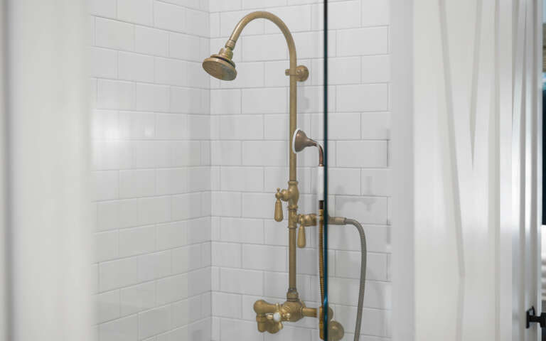 Step into your elegant bathroom featuring a luxurious brass rainfall shower system with vintage-inspired fixtures against classic white subway tiles.