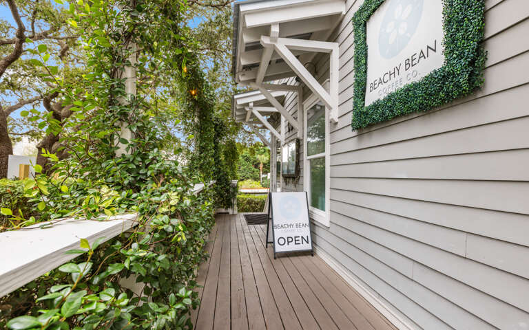 Modern beach property entrance with coastal charm and lush landscaping creates an inviting arrival experience.