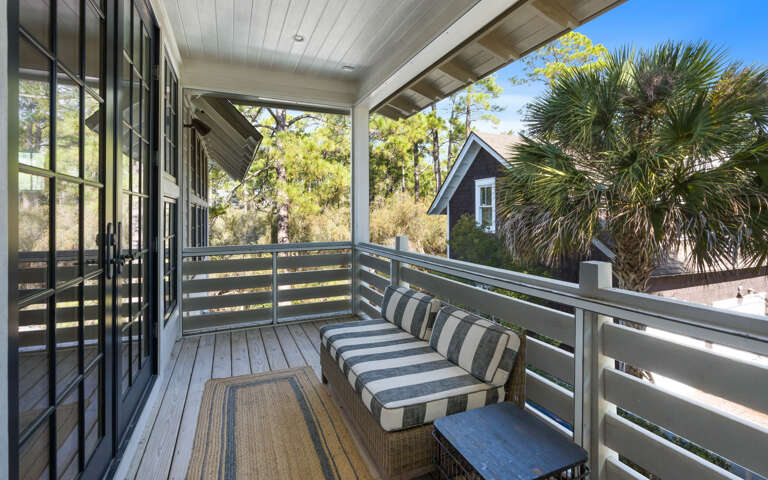 Step onto your private covered balcony with striped cushioned seating, where you can unwind while enjoying peaceful views of neighboring homes and lush palm trees.