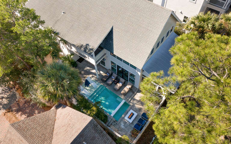 Aerial view of this stunning coastal retreat featuring a sparkling pool surrounded by lush tropical landscaping and mature palm trees.