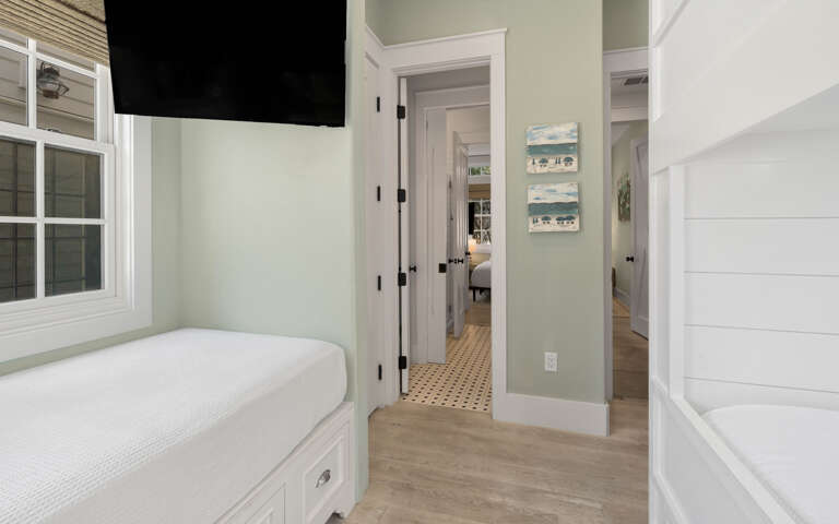 Your cozy bedroom features a built-in window seat perfect for morning coffee, with charming coastal artwork and warm wood floors throughout.