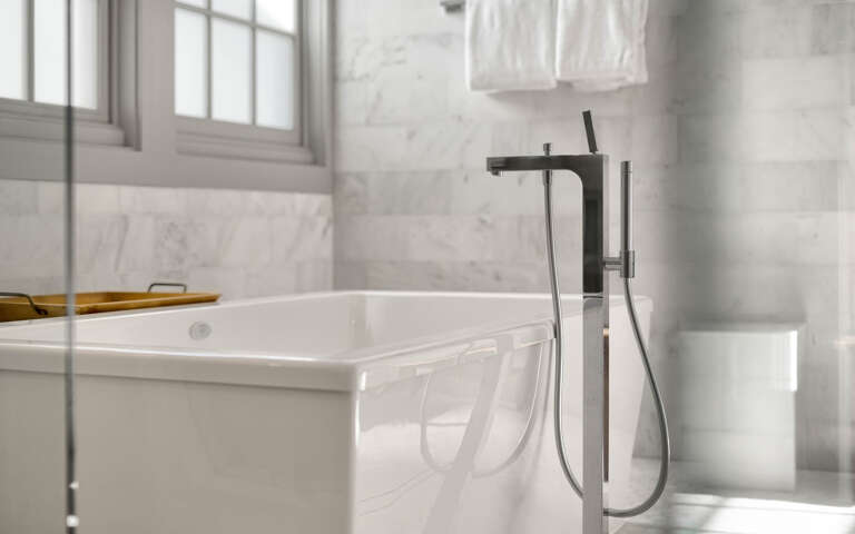 Sink into the sleek marble bathtub where natural light streams through elegant windows, creating your perfect retreat.