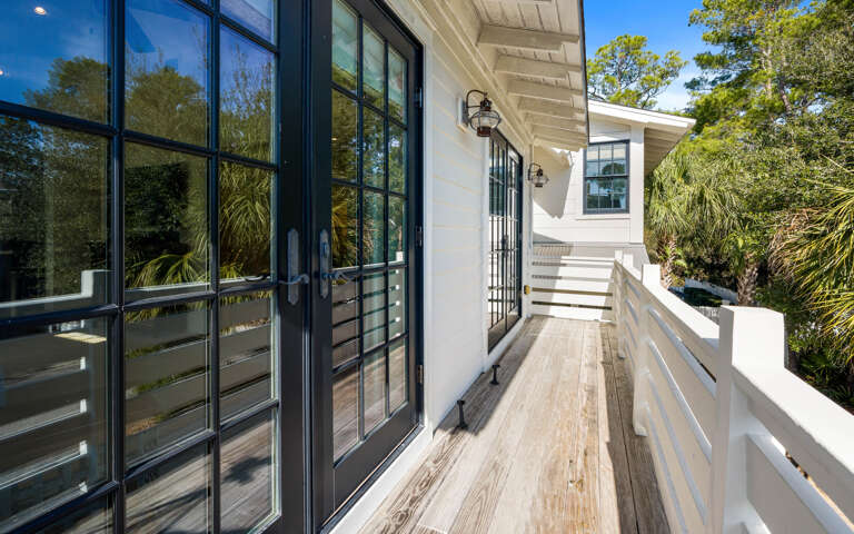 Step onto your private balcony where warm wood decking and white railings create the perfect spot to sip morning coffee surrounded by lush greenery.
