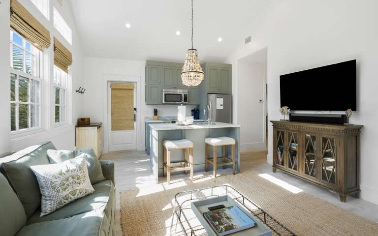 Your elegant open-plan living space features soft green hues, natural light, and a crystal chandelier creating the perfect retreat.