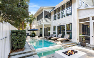 Elegant home features a private pool and fire pit surrounded by tropical landscaping for ultimate relaxation.