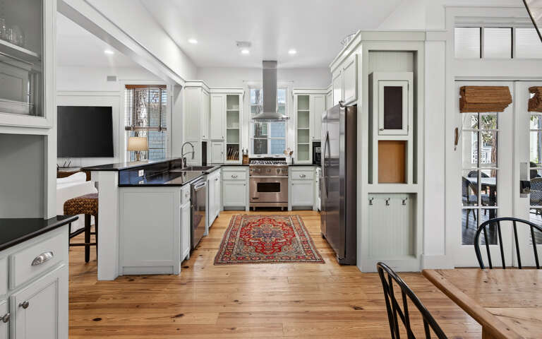 Your gourmet kitchen invites culinary adventures with premium appliances, spacious counters, and charming vintage rug on warm hardwood floors.