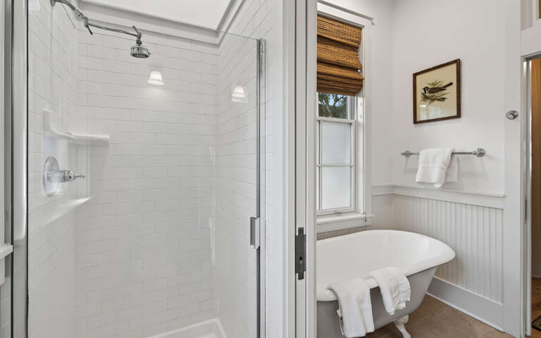 Step into your pristine bathroom sanctuary with a rainfall shower, charming subway tiles, and natural light streaming through bamboo shades.