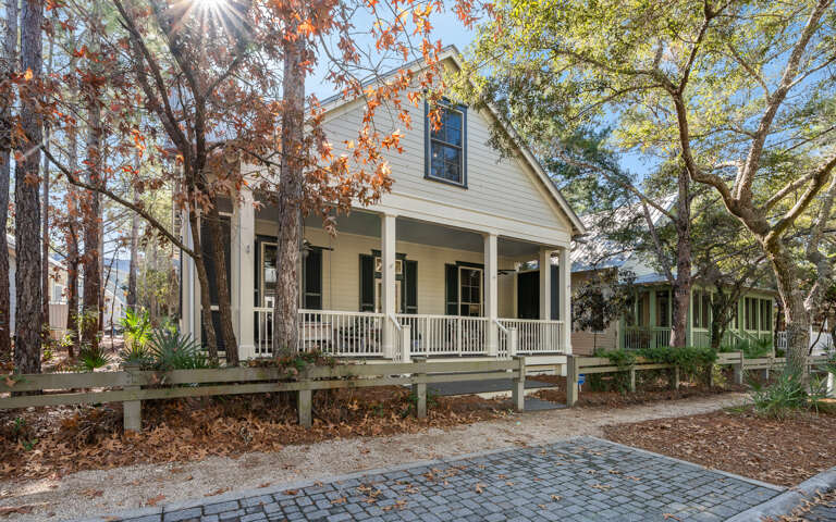 Charming cottage nestled among towering trees, featuring a welcoming front porch where you can unwind and soak in the peaceful woodland setting.