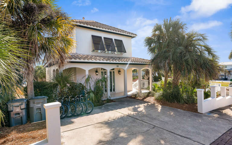 Tropical vacation villa with Mediterranean charm, surrounded by lush palm trees and tropical landscaping in a peaceful residential setting.