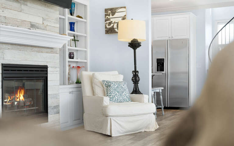 Curl up in your cozy reading chair beside the crackling fireplace, where coastal charm meets comfort in this beautifully designed living space.