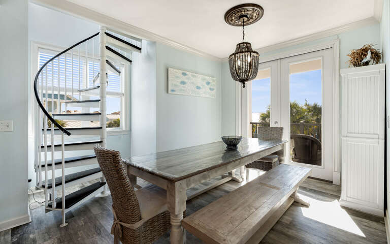Gather around this beautiful farmhouse dining table where natural light streams through coastal windows, creating the perfect space for memorable meals with family.
