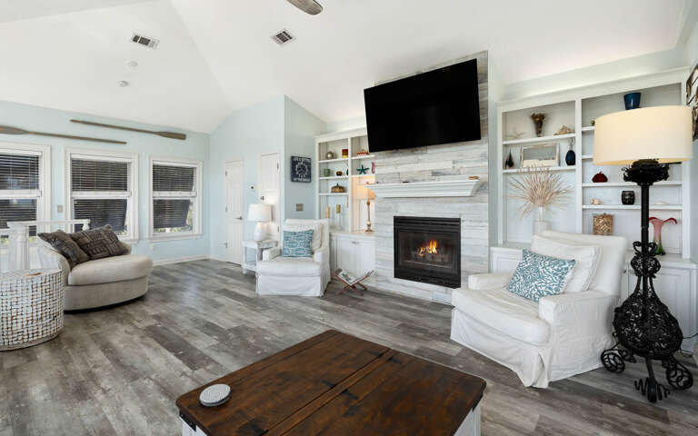 Sink into plush seating beside your crackling fireplace, where built-in shelving displays your treasures and soft lighting creates the perfect ambiance.