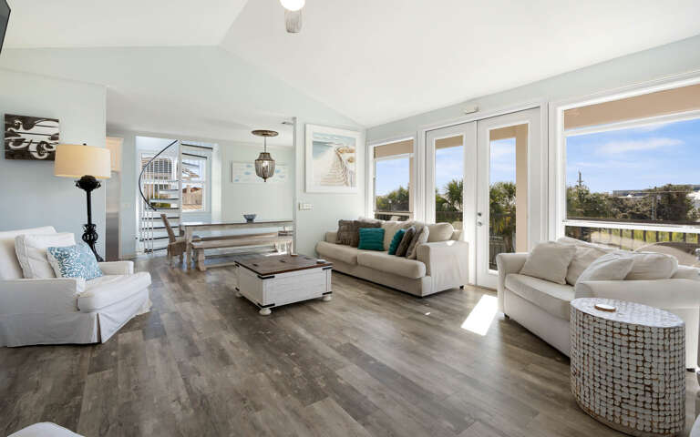 Sink into plush white sofas bathed in natural light, where floor-to-ceiling windows frame peaceful treetop views for your perfect getaway.