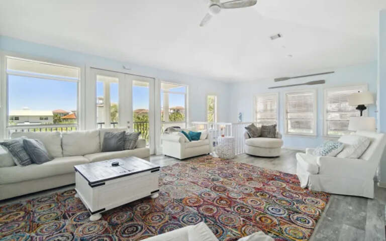 Sink into plush white sofas in your bright living room, where colorful rugs warm polished floors and ocean breezes flow through French doors.