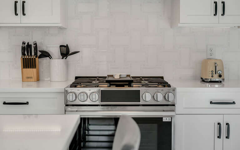 Cook your favorite meals in this modern kitchen featuring a professional gas range and sleek marble countertops.