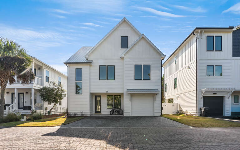 Modern coastal home featuring clean white siding and metal roof in a family-friendly neighborhood with palm trees.