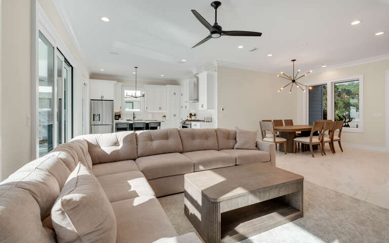 Relax in your spacious open-concept living area with plush sectional seating, modern ceiling fan, and seamless flow to the gourmet kitchen.