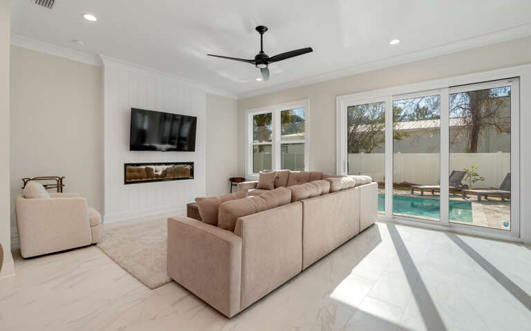 Sink into plush seating while enjoying your private pool view through floor-to-ceiling windows in this bright, modern living space.