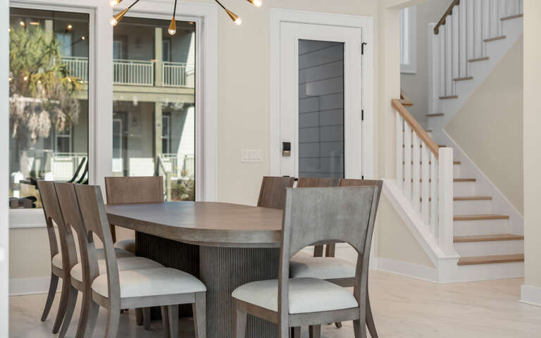 Gather around this elegant dining table for memorable meals, with natural light streaming through windows and a cozy staircase nearby.
