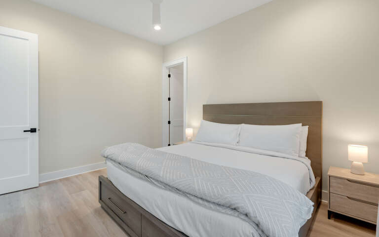 Sink into crisp white linens and wake up refreshed in your peaceful bedroom with modern wood furnishings and soft lighting.