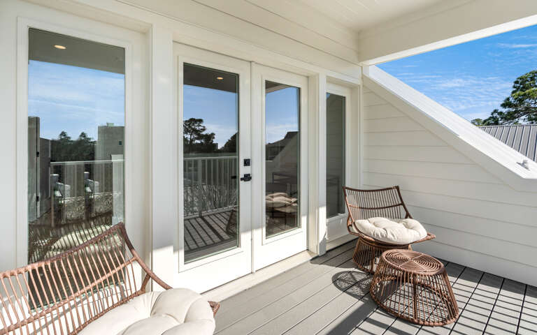 Unwind on your private balcony with stylish rattan seating, where floor-to-ceiling windows flood your space with natural light.