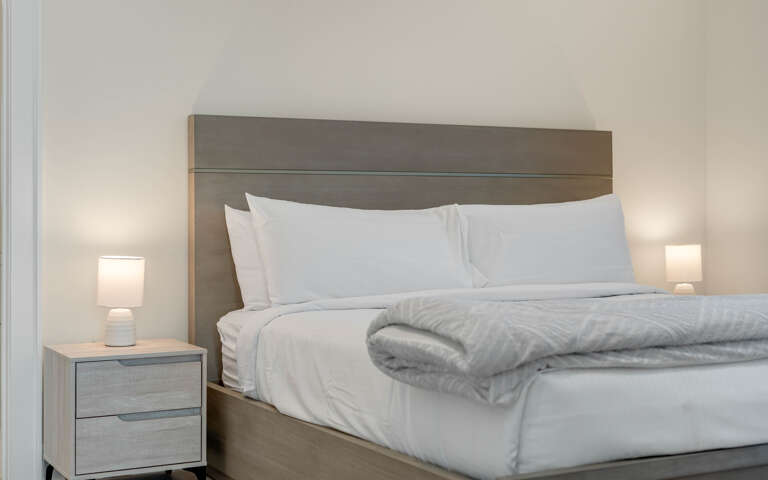 Sink into crisp white linens and plush bedding, where soft lighting creates your perfect retreat for restful nights.