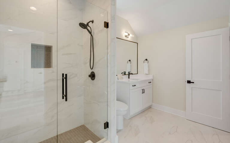 Step into your pristine private bathroom featuring a spacious glass shower and sleek vanity with modern fixtures.