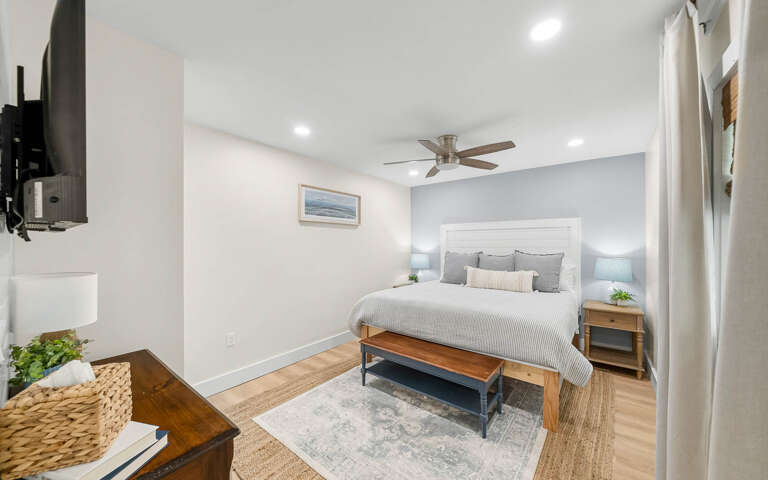 Drift off to sleep in your serene bedroom, where soft coastal artwork and gentle ceiling fan create the perfect restful retreat.