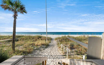 A pristine beach pathway leads directly to white sand and turquoise waters from this beachfront property.