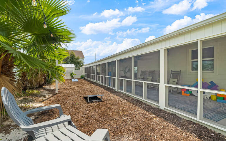Your private screened porch overlooks a tropical courtyard with palm trees and modern seating, perfect for morning coffee or evening relaxation.